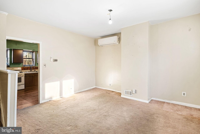 spare room featuring light colored carpet, an AC wall unit, and sink