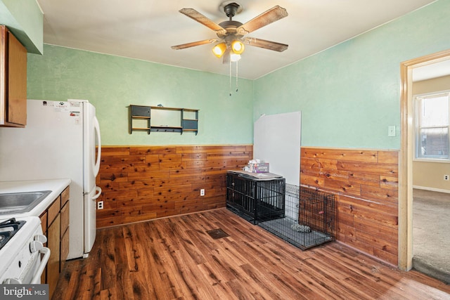 kitchen with wood walls, ceiling fan, dark hardwood / wood-style floors, and white appliances