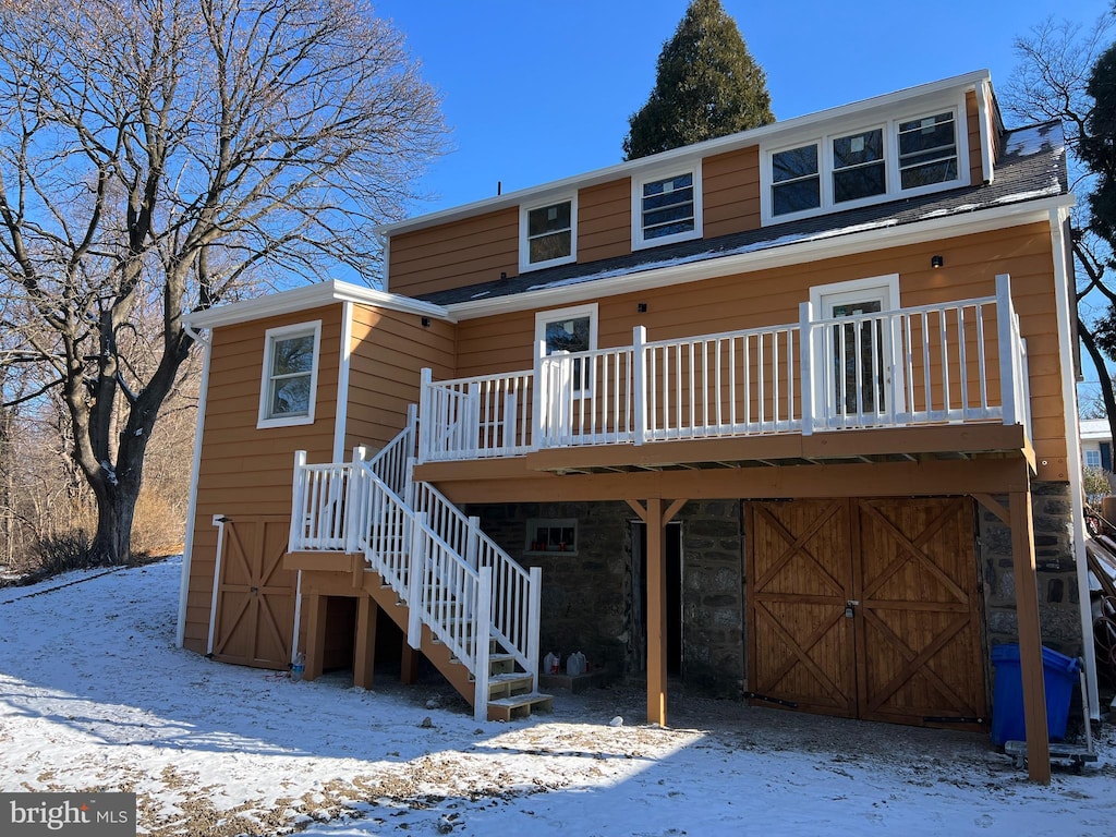 snow covered back of property featuring a deck