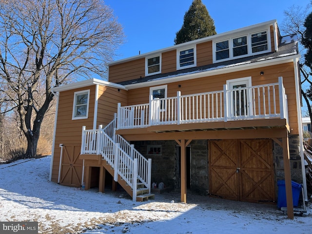 snow covered back of property with a wooden deck