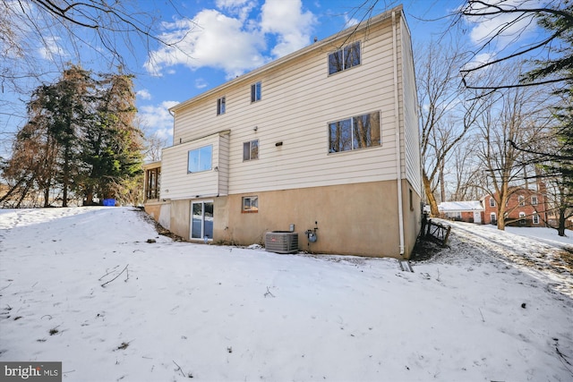 snow covered back of property featuring central air condition unit