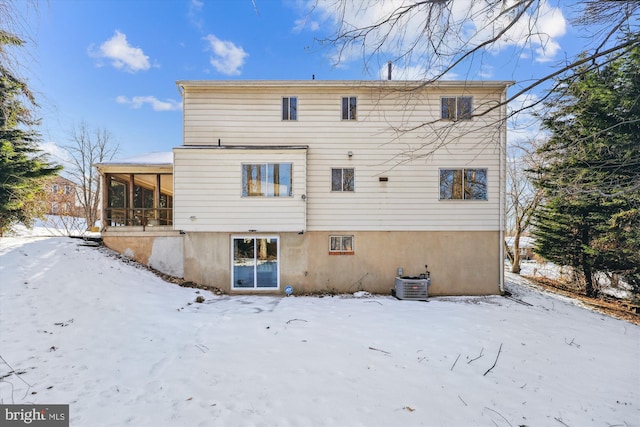 snow covered back of property featuring central air condition unit