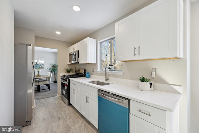 kitchen with sink, stainless steel appliances, white cabinetry, and a notable chandelier