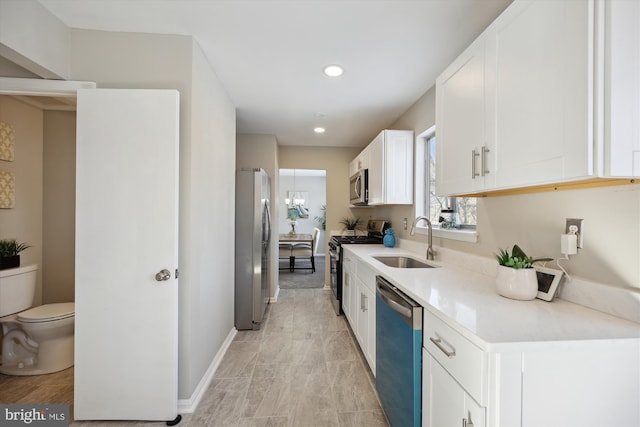 kitchen with sink, stainless steel appliances, white cabinets, and a notable chandelier