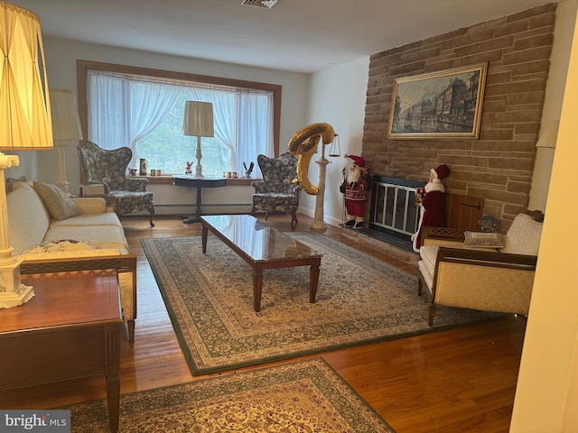 sitting room featuring a baseboard heating unit, dark hardwood / wood-style floors, and a stone fireplace