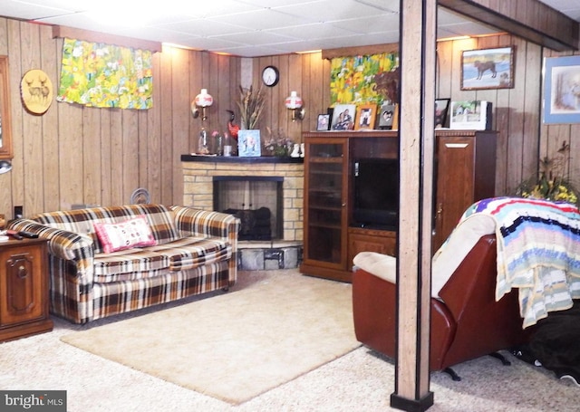 living room with light carpet, a paneled ceiling, a fireplace, and wood walls