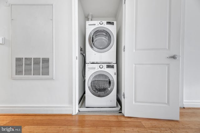 laundry area featuring stacked washing maching and dryer and light wood-type flooring