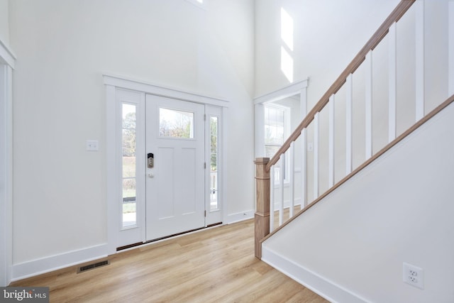 foyer featuring a towering ceiling and light hardwood / wood-style flooring