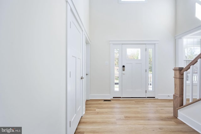 foyer entrance with a towering ceiling and light hardwood / wood-style flooring