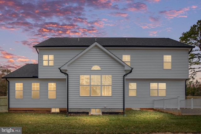 back house at dusk with a lawn