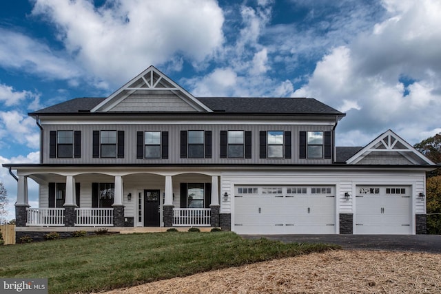 view of front of home with a garage, covered porch, and a front lawn