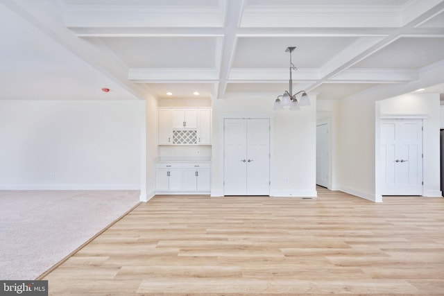 interior space with beamed ceiling, ornamental molding, coffered ceiling, a notable chandelier, and light hardwood / wood-style floors