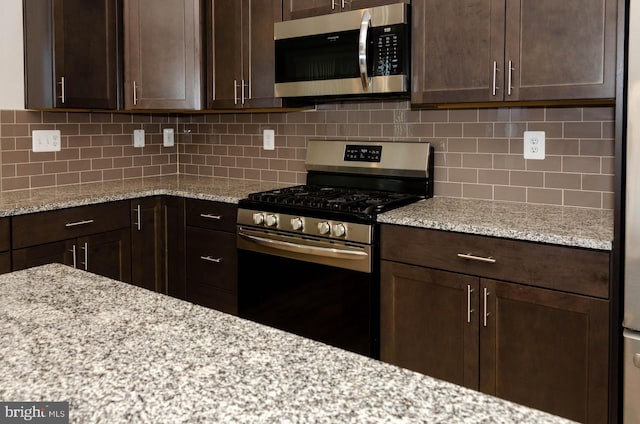 kitchen featuring tasteful backsplash, dark brown cabinetry, appliances with stainless steel finishes, and light stone countertops