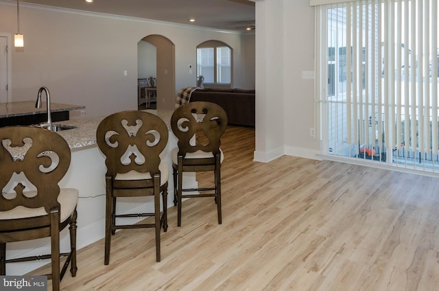 dining room featuring crown molding, sink, and light hardwood / wood-style flooring