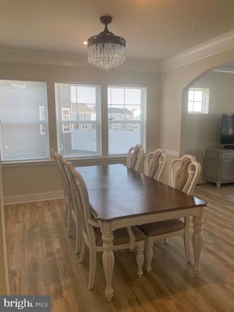 dining space with ornamental molding, hardwood / wood-style floors, and a chandelier