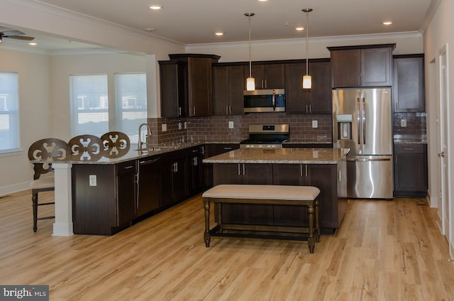 kitchen featuring appliances with stainless steel finishes, a center island, pendant lighting, and a breakfast bar