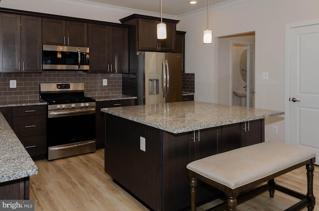 kitchen with a kitchen bar, light stone counters, decorative light fixtures, a center island, and stainless steel appliances