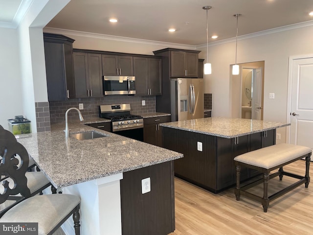 kitchen with decorative light fixtures, stainless steel appliances, a breakfast bar, and a kitchen island