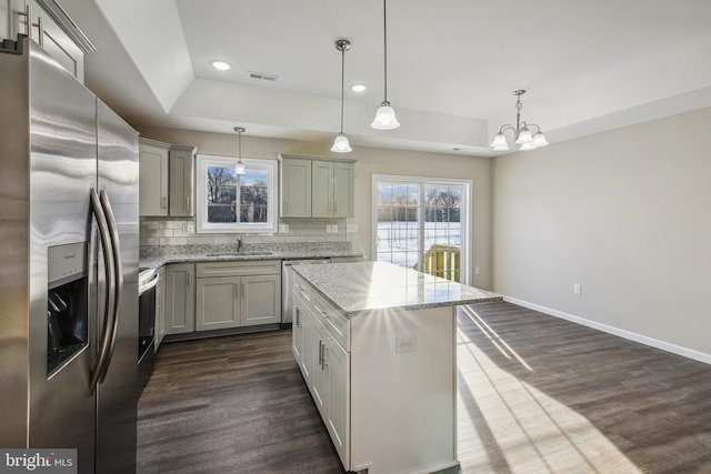 kitchen featuring pendant lighting, appliances with stainless steel finishes, a kitchen island, decorative backsplash, and sink