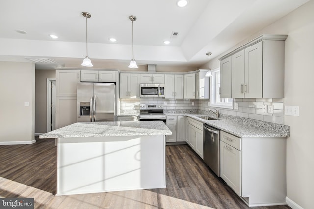 kitchen with decorative light fixtures, a kitchen island, sink, stainless steel appliances, and light stone counters