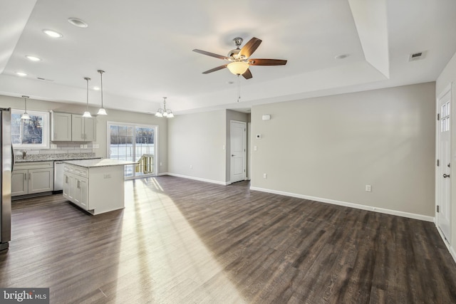 kitchen featuring backsplash, a center island, a tray ceiling, hanging light fixtures, and dark wood-type flooring