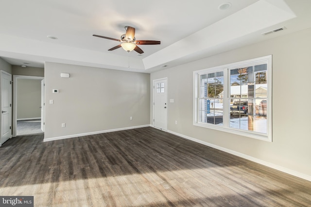 spare room with ceiling fan, dark hardwood / wood-style flooring, and a raised ceiling