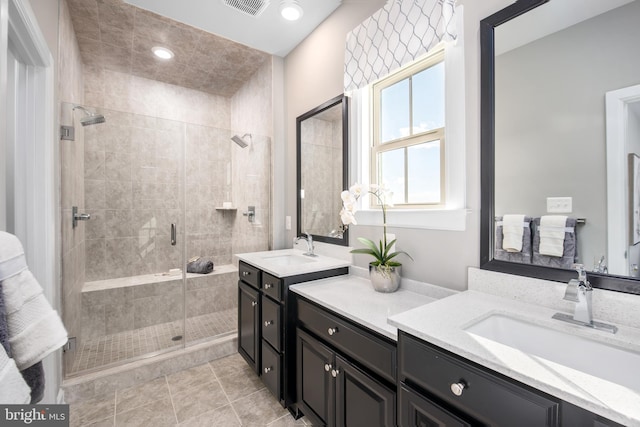 bathroom with walk in shower, vanity, and tile patterned flooring