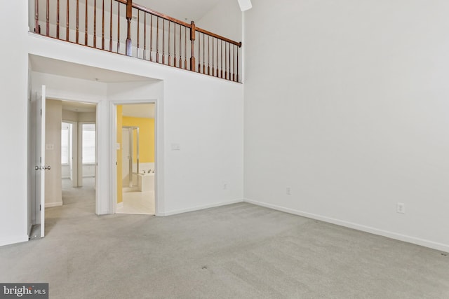 carpeted spare room with a towering ceiling