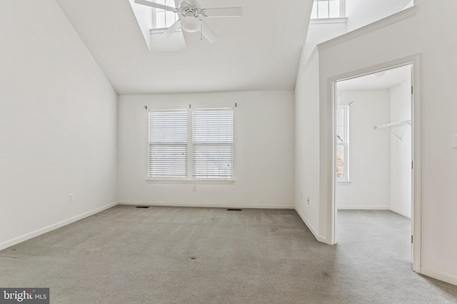 carpeted spare room with ceiling fan and vaulted ceiling