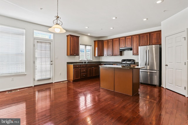 kitchen with sink, range, a center island, decorative light fixtures, and stainless steel refrigerator