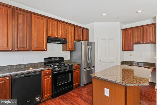 kitchen featuring dark hardwood / wood-style flooring, black appliances, a center island, and stone counters