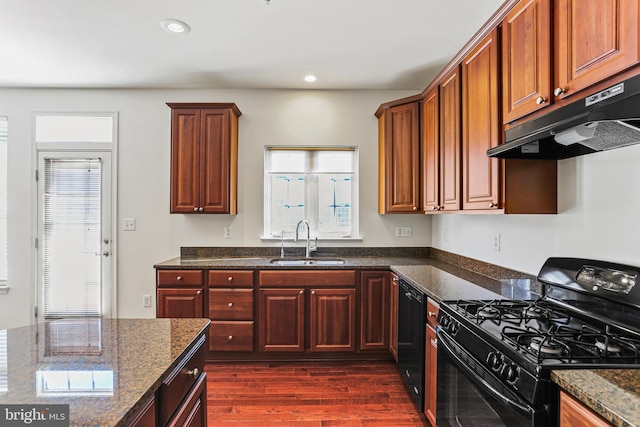 kitchen with sink, dark stone countertops, dark hardwood / wood-style flooring, and black appliances