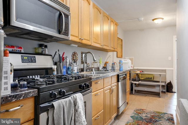 kitchen featuring light tile patterned floors, appliances with stainless steel finishes, light brown cabinets, radiator, and sink