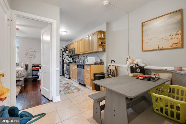 kitchen featuring light tile patterned floors, a breakfast bar area, appliances with stainless steel finishes, light brown cabinets, and sink