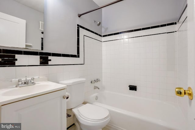 full bathroom with tiled shower / bath combo, vanity, backsplash, tile walls, and toilet