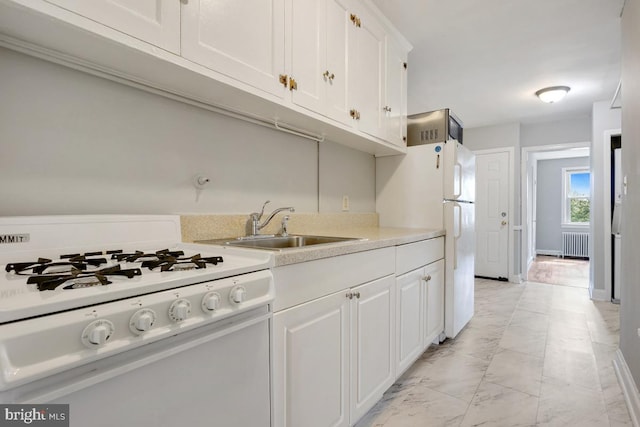 kitchen with white cabinets, radiator, sink, and white appliances