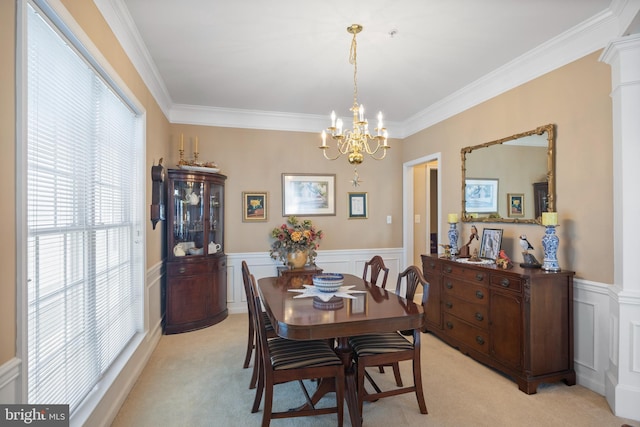 carpeted dining space with ornamental molding, a chandelier, and ornate columns