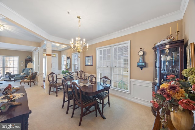 carpeted dining room featuring an inviting chandelier, crown molding, and decorative columns