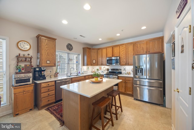 kitchen with appliances with stainless steel finishes, a breakfast bar area, sink, and a kitchen island