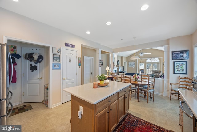 kitchen with stainless steel fridge, ceiling fan, decorative columns, a kitchen island, and vaulted ceiling