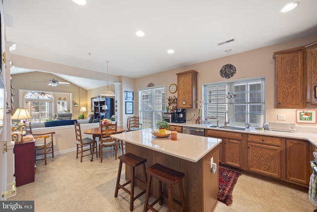 kitchen featuring lofted ceiling, sink, a kitchen breakfast bar, a kitchen island, and stainless steel dishwasher