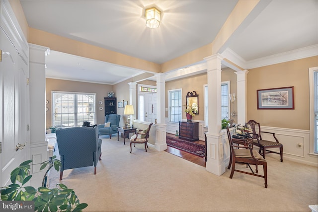 carpeted living room with crown molding and ornate columns