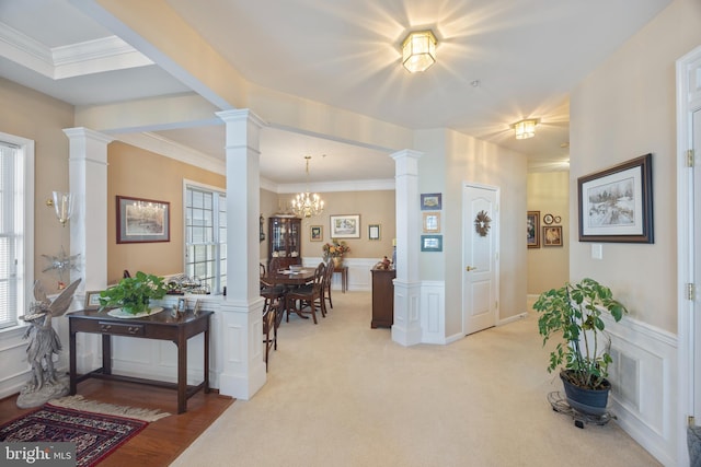 interior space with ornate columns, crown molding, light colored carpet, and a notable chandelier