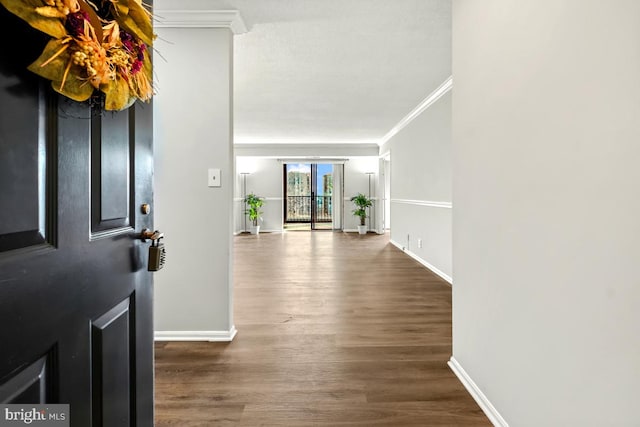 foyer with crown molding, baseboards, and wood finished floors