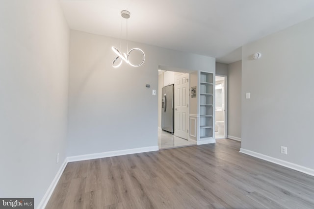 unfurnished room with light hardwood / wood-style floors and a chandelier