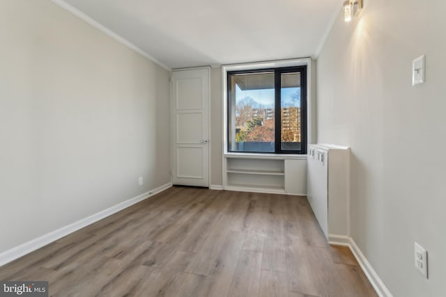 empty room with crown molding and light hardwood / wood-style flooring