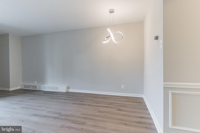 unfurnished dining area with a notable chandelier and light wood-type flooring