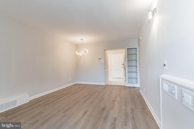 spare room featuring light hardwood / wood-style floors and an inviting chandelier