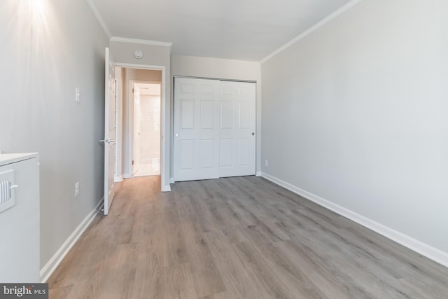 unfurnished bedroom featuring a closet, ornamental molding, and light hardwood / wood-style floors