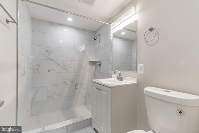 bathroom featuring toilet, a tile shower, and vanity